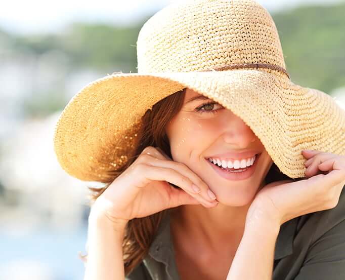 smiling woman pulling her hat over part of her face