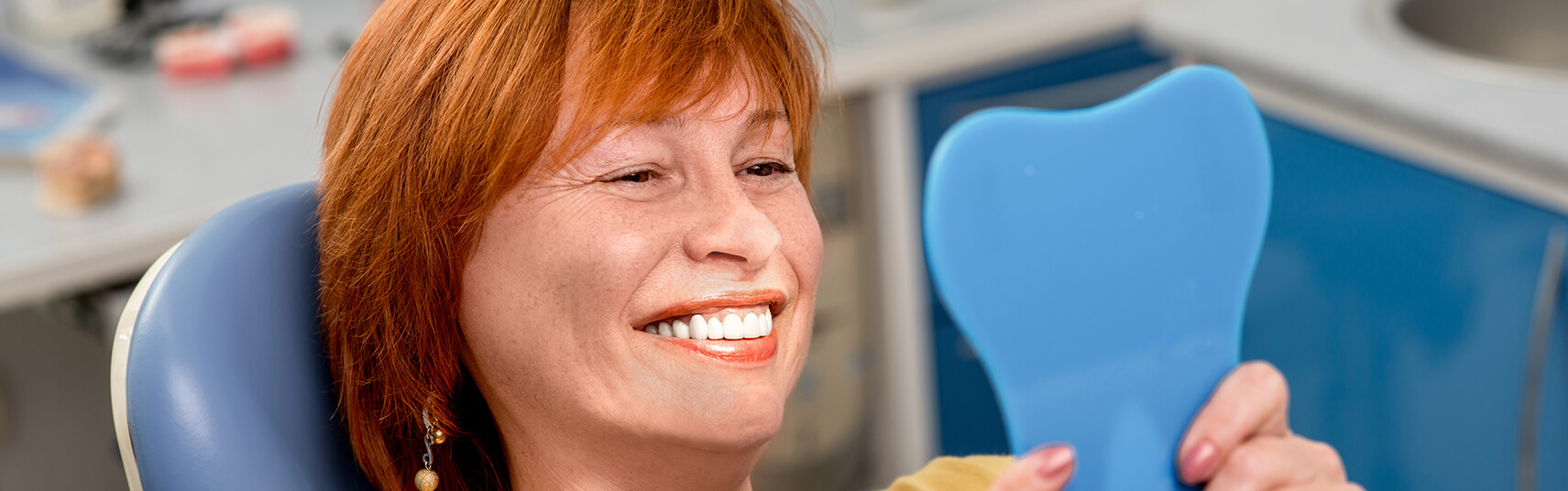 woman examining her smile in a mirror
