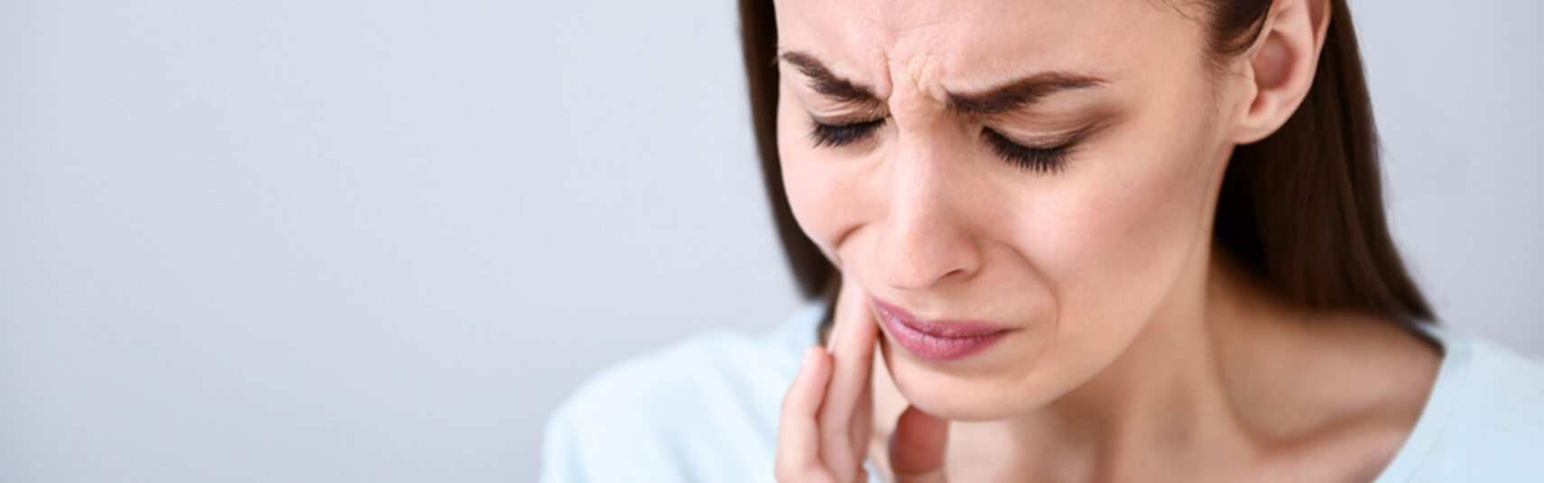 woman holding her jaw in pain