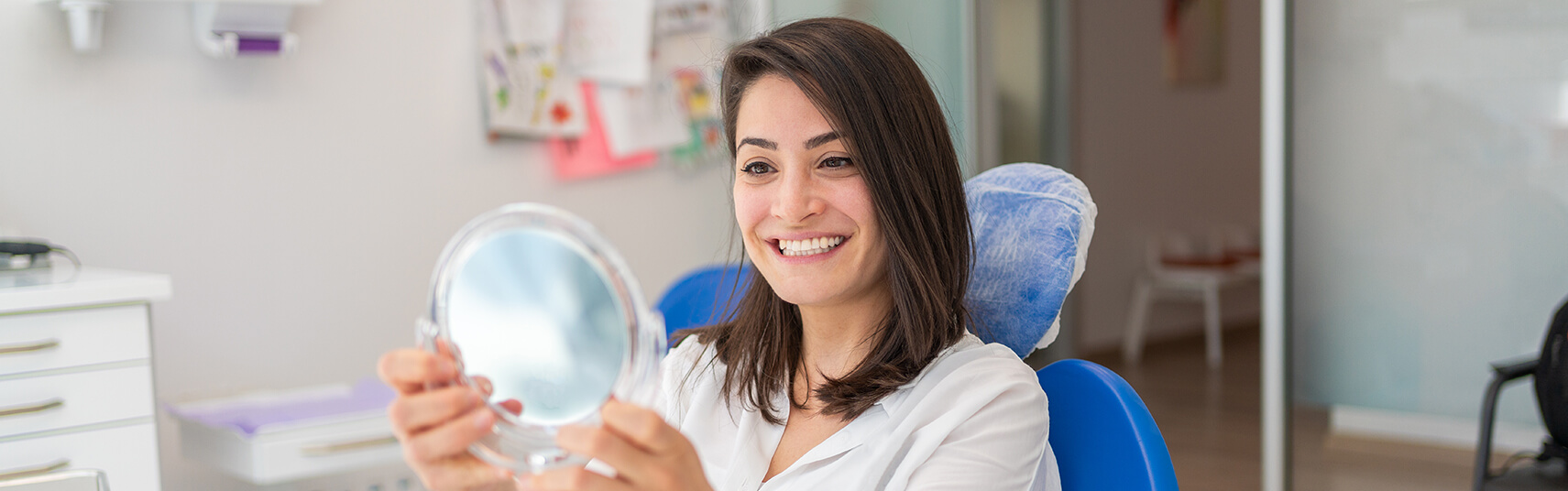 woman examining her smile in a mirror